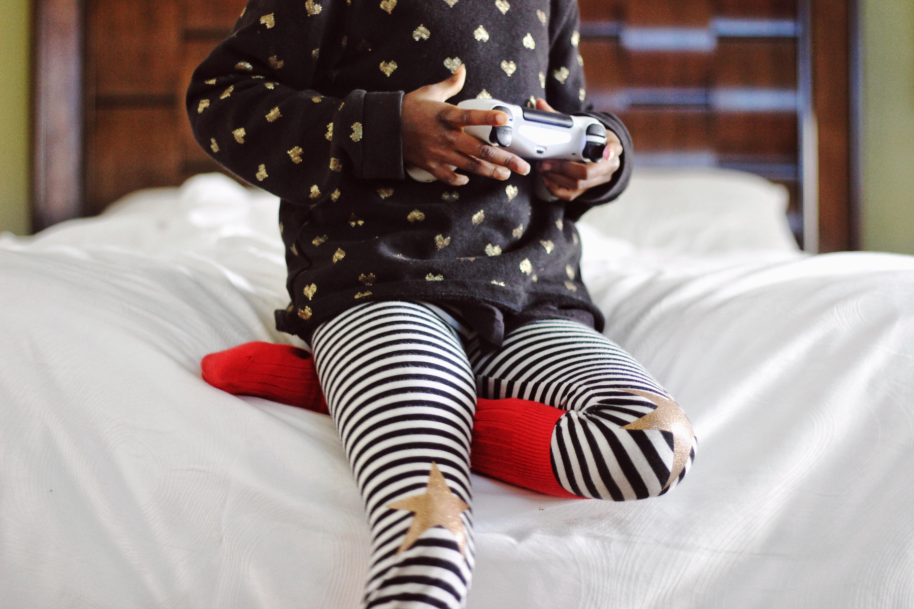child playing video games on bed